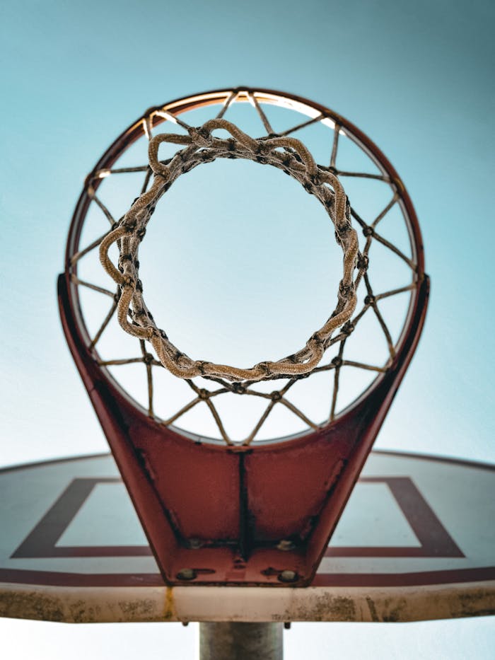 menu-01 Looking up through a basketball hoop with a clear sky background.